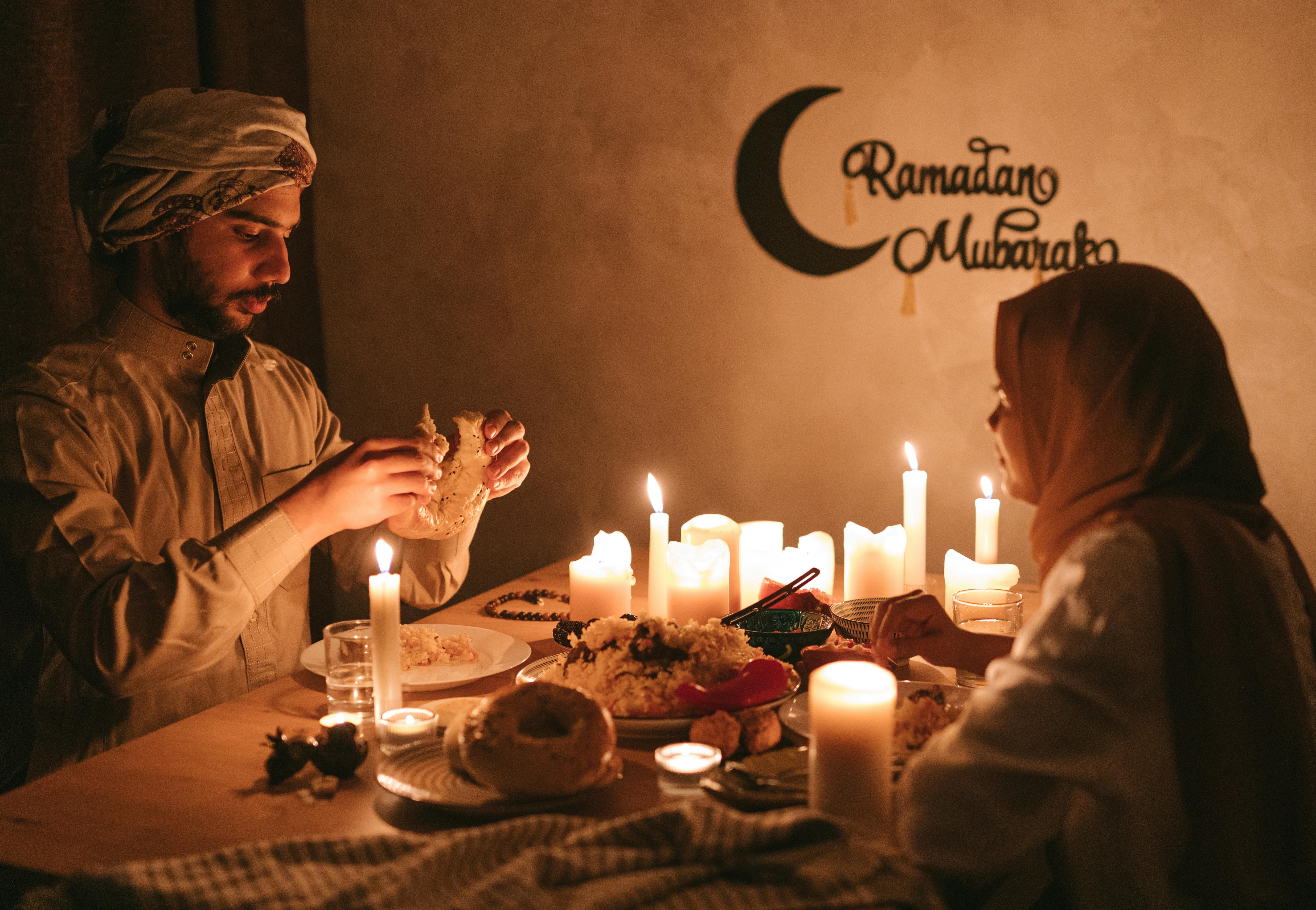 photo of couple eating food at night by several lit candles at Ramadan photo of couple eating food at night by several lit candles at Ramadan